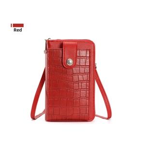 Detail of red crocodile embossed crossbody phone bag with metal snap and zipper