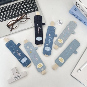 Detail of denim pencil case with elastic strap fixed on notebook in various blue shades