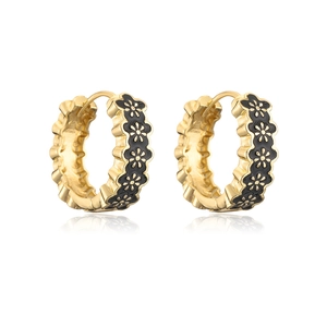 Close-up of gold-plated hoop earrings with black enamel flower pattern on white background