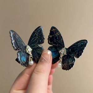 Detail of blue butterfly hair clip with rhinestones and pearl pendant on a hand