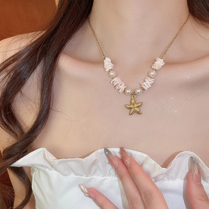 Macro detail of starfish pendant and pearls on a gold chain necklace for women