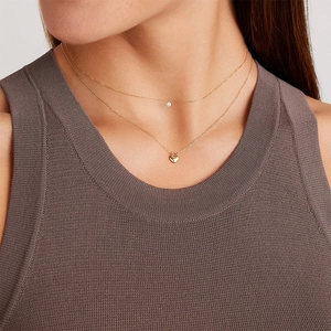 Detail of layered gold heart necklace set with sparkling crystal on elegant model