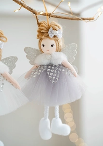 Detail of Christmas tulle angel ornament with sequin wings hanging on illuminated branch