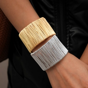 Detail of gold and silver multi-layer geometric wire wrap cuff bracelets on wrist