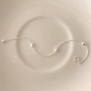 Detailed view of S925 sterling silver olive bead bracelet on a minimalist ceramic plate