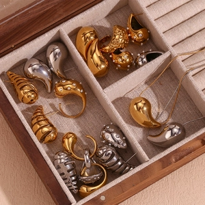 Macro detail of 18K gold and silver waterdrop earrings in a wooden jewelry box