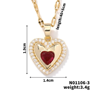 Macro shot of gold heart pendant with red crystal and white zircon micro-inlay