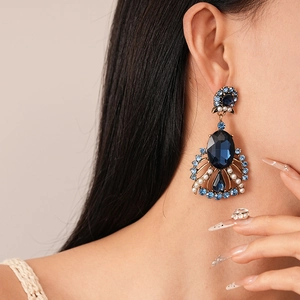 Detailed close-up of retro blue gemstone drop earrings with pearls on model's ear