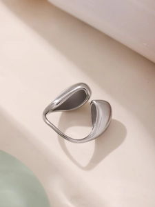 Close-up of a silver streamlined open ring with liquid metal texture on ivory background