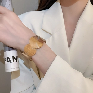 Detail of wide gold cuff bracelet with concentric circular texture on model wrist