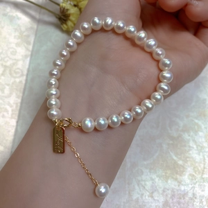 Macro detail of baroque pearl bracelet with gold lobster clasp and adjustable metal chain