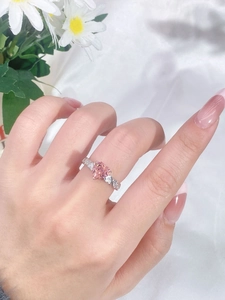 Close-up of heart-shaped pink gemstone ring with diamond accents on a silver band
