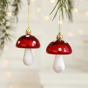 Red and white mushroom Christmas ornaments hanging on a festive pine tree branch