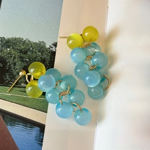 Gros plan de boucles d'oreilles en résine perlée jaune et bleue sur un livre