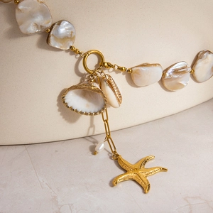 Macro shot of 18k gold plated stainless steel chain with sea shell and starfish charms
