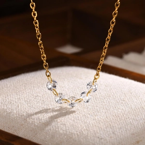 Macro shot of gold stainless steel necklace with five round white cubic zirconia stones