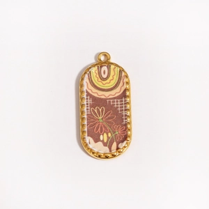 Close-up of golden oval koi fish pendant with intricate floral fabric inlay and beaded edge