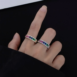 Close-up of gold and silver rings with colorful zircon and white side diamonds on hand