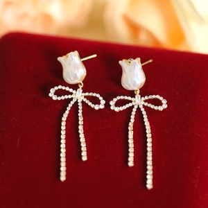 Macro shot of gold tulip earrings with rhinestone bow and long tassel details