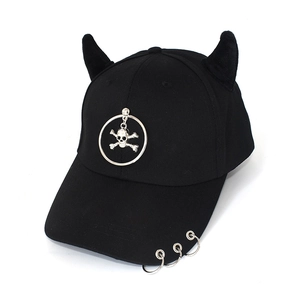 Detail of black cotton baseball cap with devil horns and metal rings with skull pendant