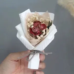 Detail of mini dried red rose and gypsophila bouquet in elegant white paper packaging