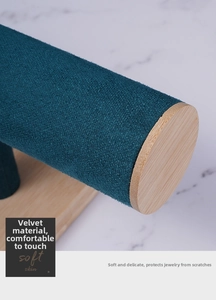 Detail of teal velvet jewelry display stand with light natural wood base and accents