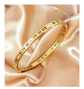 Close-up of gold Roman numeral bangle with inlaid sparkling crystals on silk background