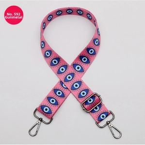 Detail of pink shoulder strap with blue evil eye patterns and gunmetal buckles