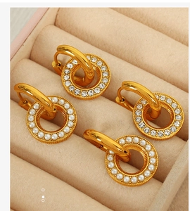 Detail of gold hollow geometric earrings with rhinestones and pearls in a velvet box