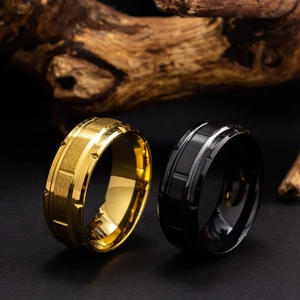 Detail of wide titanium steel rings in gold and black with grooved brushed finish