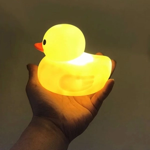 Close-up of a glowing yellow duck toy being held in hand with warm light effects