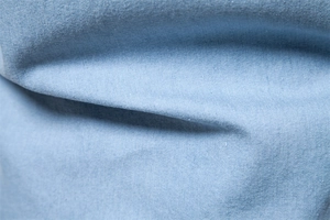 Macro shot of light blue denim shirt fabric showing detailed cotton texture and weave