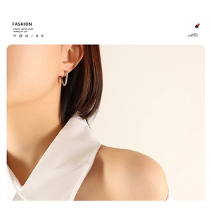 Close-up of a silver minimalist triangle earring worn by a female model with sleek metal texture