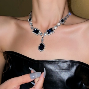 Macro detail of elegant blue teardrop and square crystal pendant on silver necklace