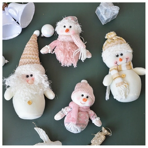 Flat-lay of pink and white plush Christmas tree ornaments featuring Santa and Snowman