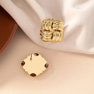 Macro detail of gold square twisted knot stud earrings with woven texture on velvet