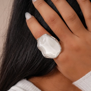 Detailed view of an irregular oval resin ring with silver-tone metal on a finger