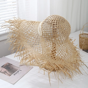 Detail of hand-woven raffia sun hat featuring hollow texture and frayed edge on wooden stand