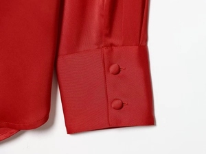 Detail of red satin shirt sleeve featuring elegant fabric-wrapped double button closure