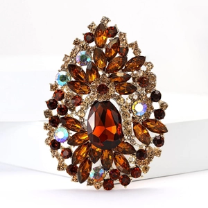 Macro detail of high-end amber rhinestone brooch with teardrop gem on gold base