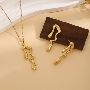 Detailed view of golden irregular molten liquid necklace and earrings on wood base
