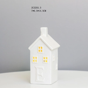 Detail of white ceramic house LED night light with letter E carving and yellow glow