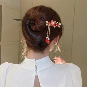 Detail of wooden hair stick with red flower and pearl tassels on elegant updo