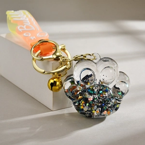 Macro detail of acrylic cat paw keychain with colorful sequins and golden bell