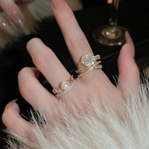 Primo piano di anello multistrato dorato con zircone e perla indossato da una modella