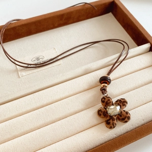 Vue macro du pendentif fleur léopard avec strass incrustés et cordon marron tressé