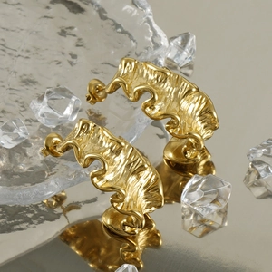 Detail of 18K gold stainless steel earrings with irregular molten lava texture design
