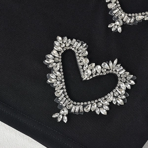 Detailed close-up of sparkling heart-shaped rhinestones on black ribbed knit fabric