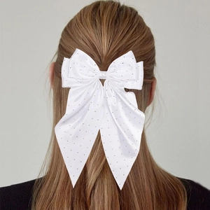 Barrette à nœud blanc élégante avec strass portée sur de longs cheveux bruns