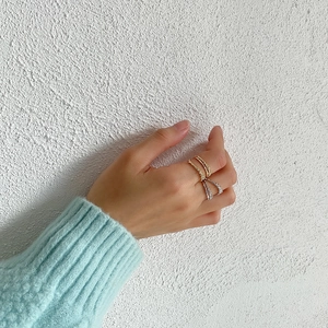 Detail of stacked gold twisted texture ring and silver zircon double row band on finger